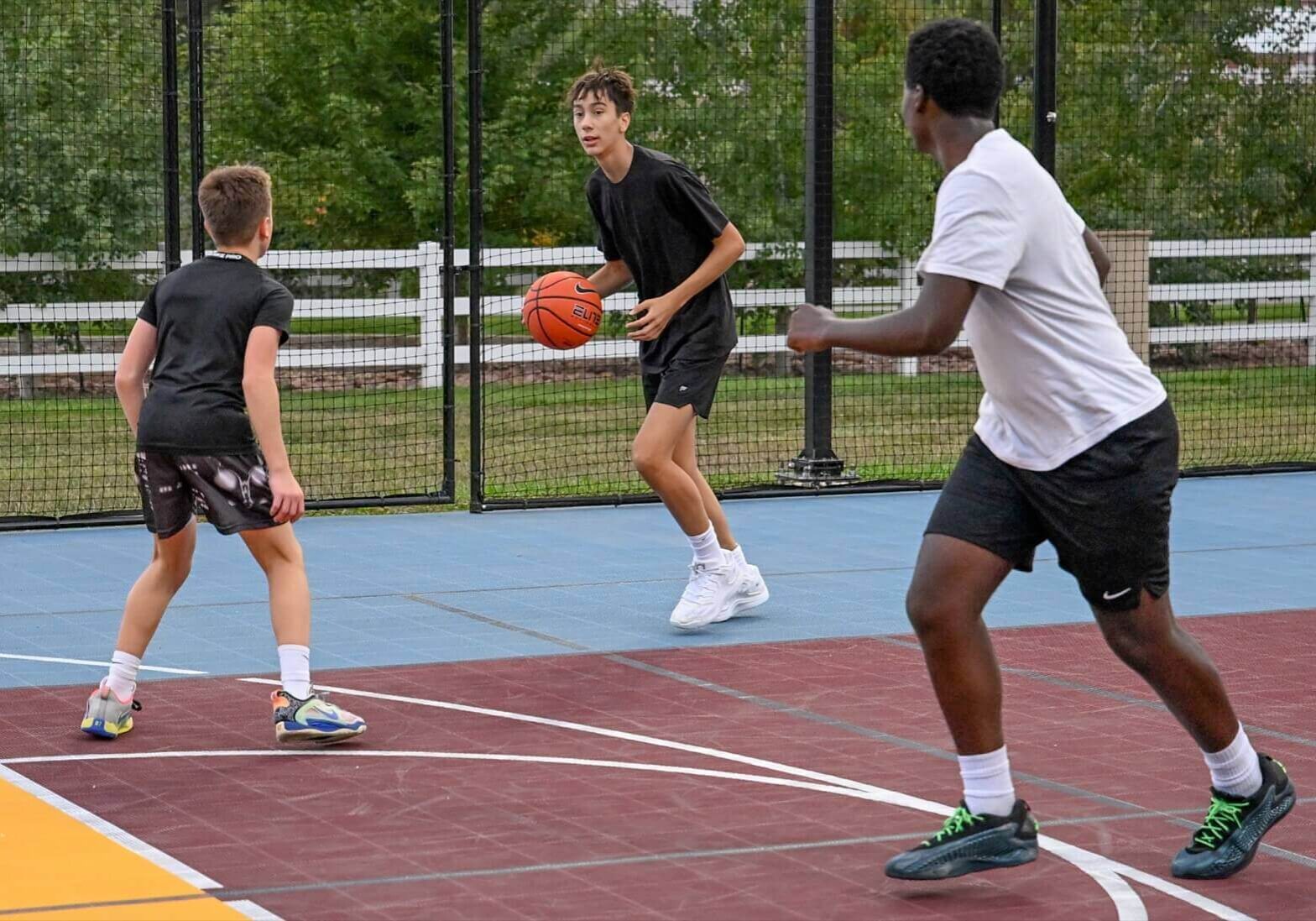 Kids play on a basketball court designed by a sports court builder